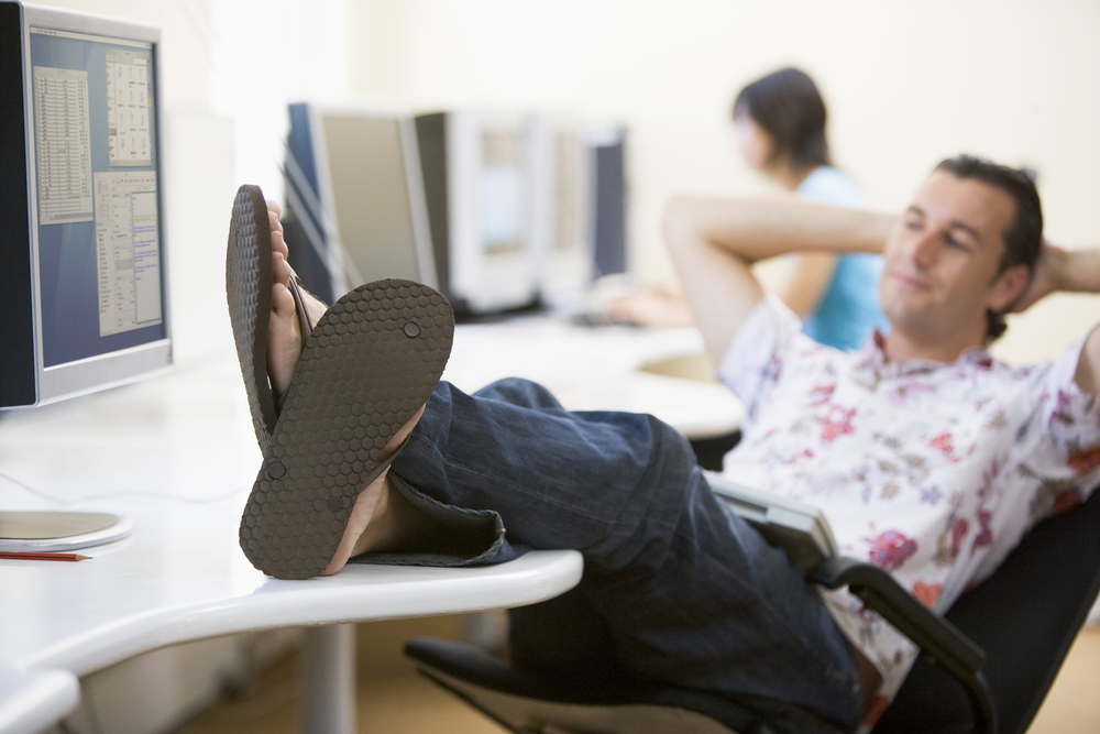 man reclining with feet crossed on his desk wearing flip flops