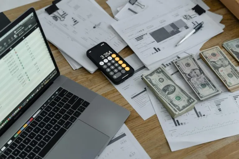 Computer, calculator and money displayed on a desk.