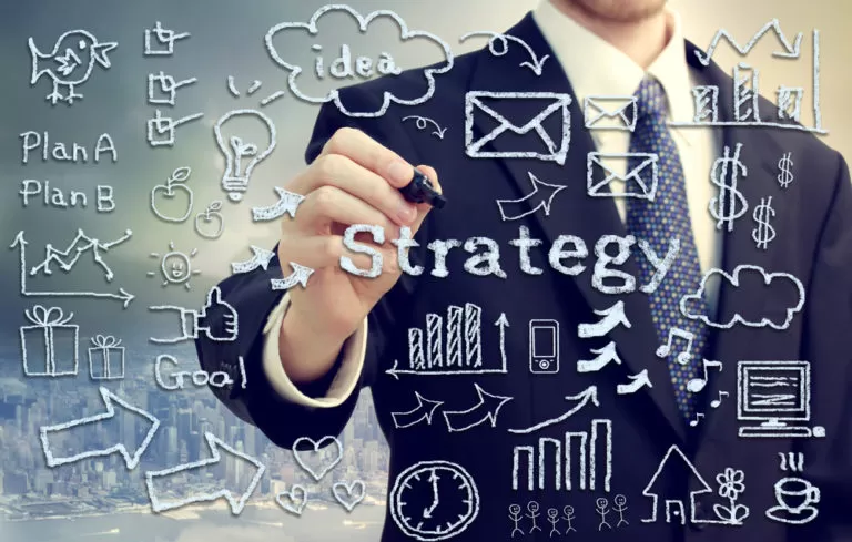 A businessman drawing a strategy plan with a marker on a transparent board