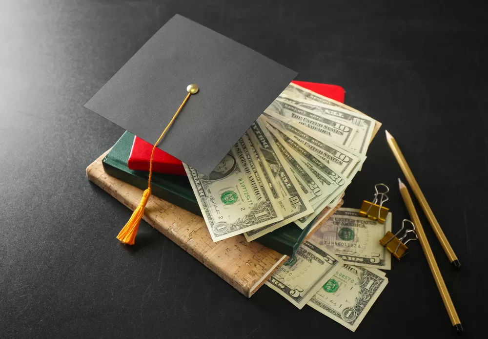graduation hat on top of money and books