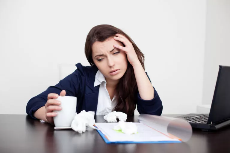frustrated woman with coffee and crumpled paper