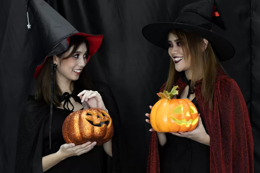 women holding pumpkins dressed up as witches