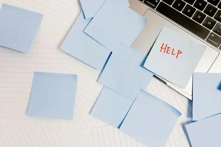 Laptop with post-it notes and one with "Help" written on it stuck to the mousepad